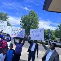 Group holding Christ is Risen and Jesus is Alive signs on a street corner