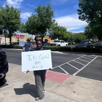 Church member holding an In God We Trust sign on the sidewalk