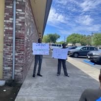 Two men holding resurrection signs beside a brick building