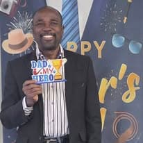 Man holding a Dad, U R My Hero sign at the Father's Day celebration