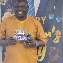 Man in gold traditional attire holding a Best Dad sign