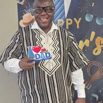 Man in traditional attire holding an I Love Dad sign